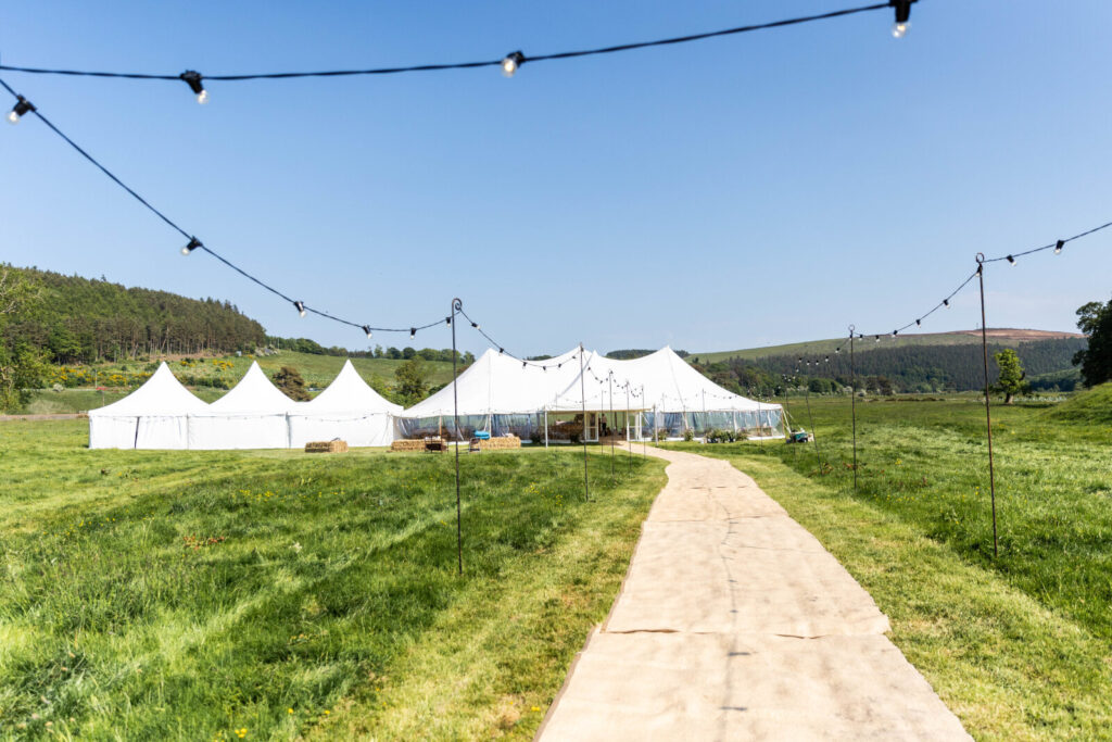a marquee on a bright day and a path lined with fairy lights for a catering event.