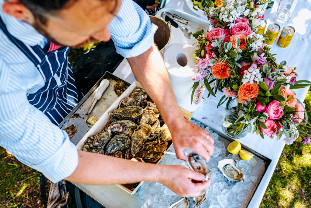 A chef shucking oysters and placing them on a bed of ice