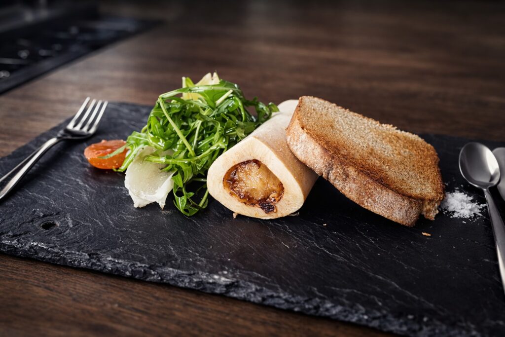 catering menu item: a starter of bone marrow, toasted bread, and salad on a board of slate
