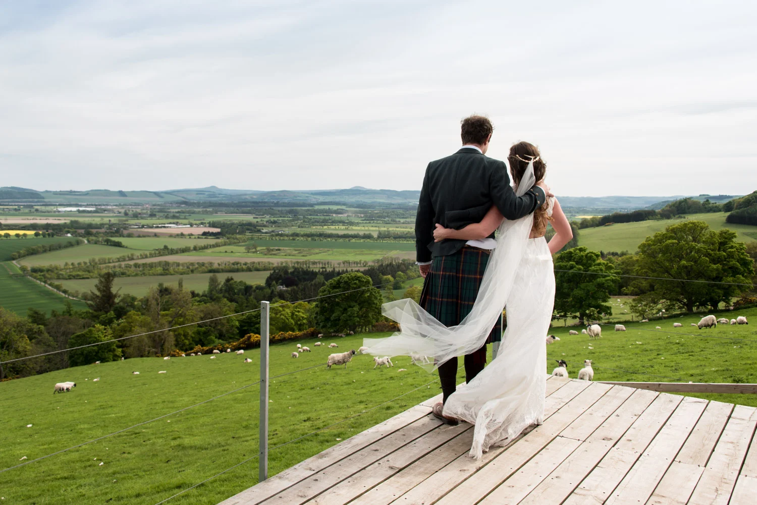 a bride and groom look out over fields