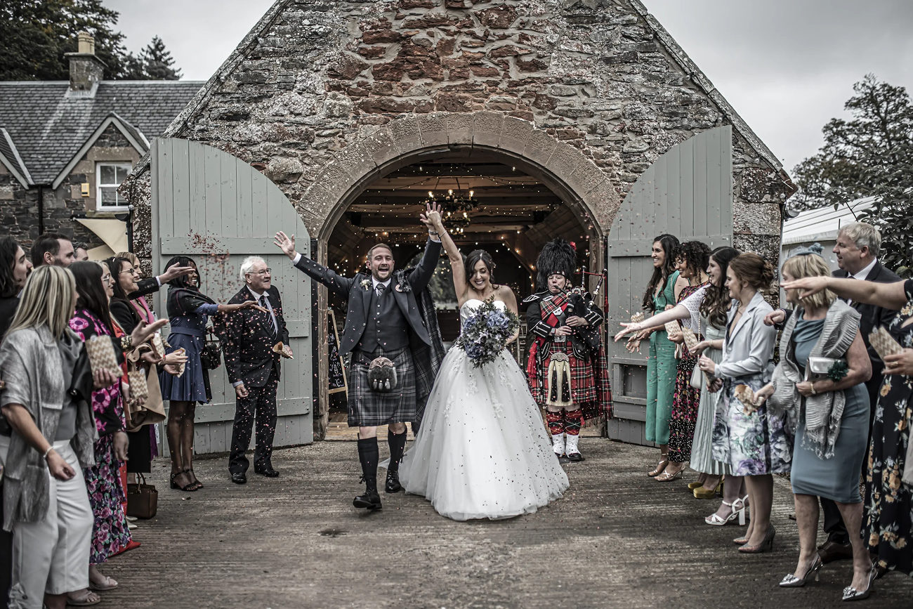a bride and groom hold hands as guests throw confetti